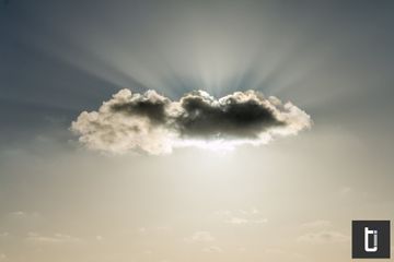 Sunlight breaking around a cloud against a muted sky.