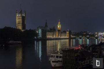 The Palace of Westminster lit at night beside the River Thames.