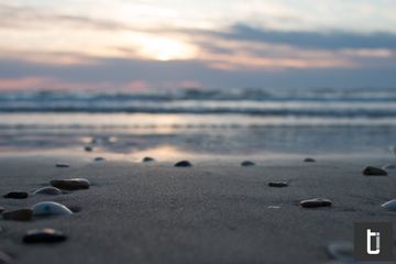 A muted cloudy sunset with a pebble and sand beach foreground.