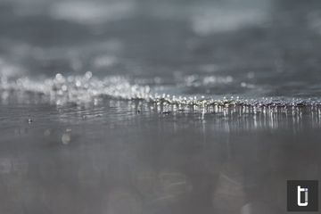 Foam from a small wave spreading over wet sand.
